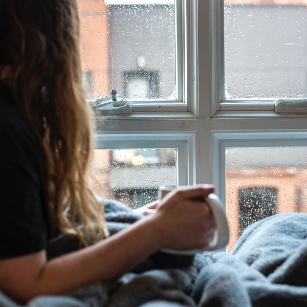 Lady in bed with hot drink in cold damp home_600sq